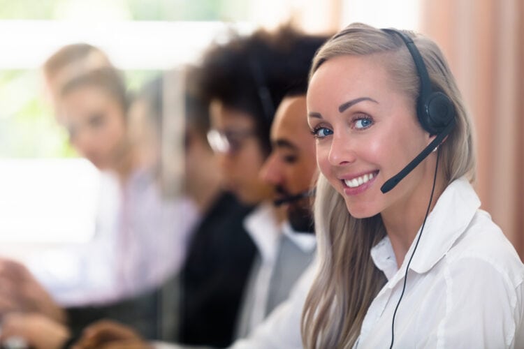 Pretty lady wearing an office headset smiling with colleagues