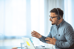 Man usind a corded monaural noise cancelling headset on an apple mac laptop