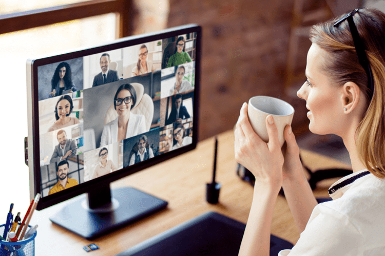 Lady holding a cup of coffe during an online meeting using a webcam
